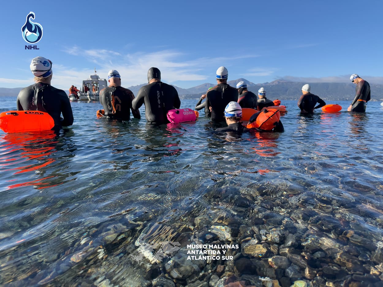 Nadadores esperando la largada, de espaldas, con las montañas de Bariloche al fondo