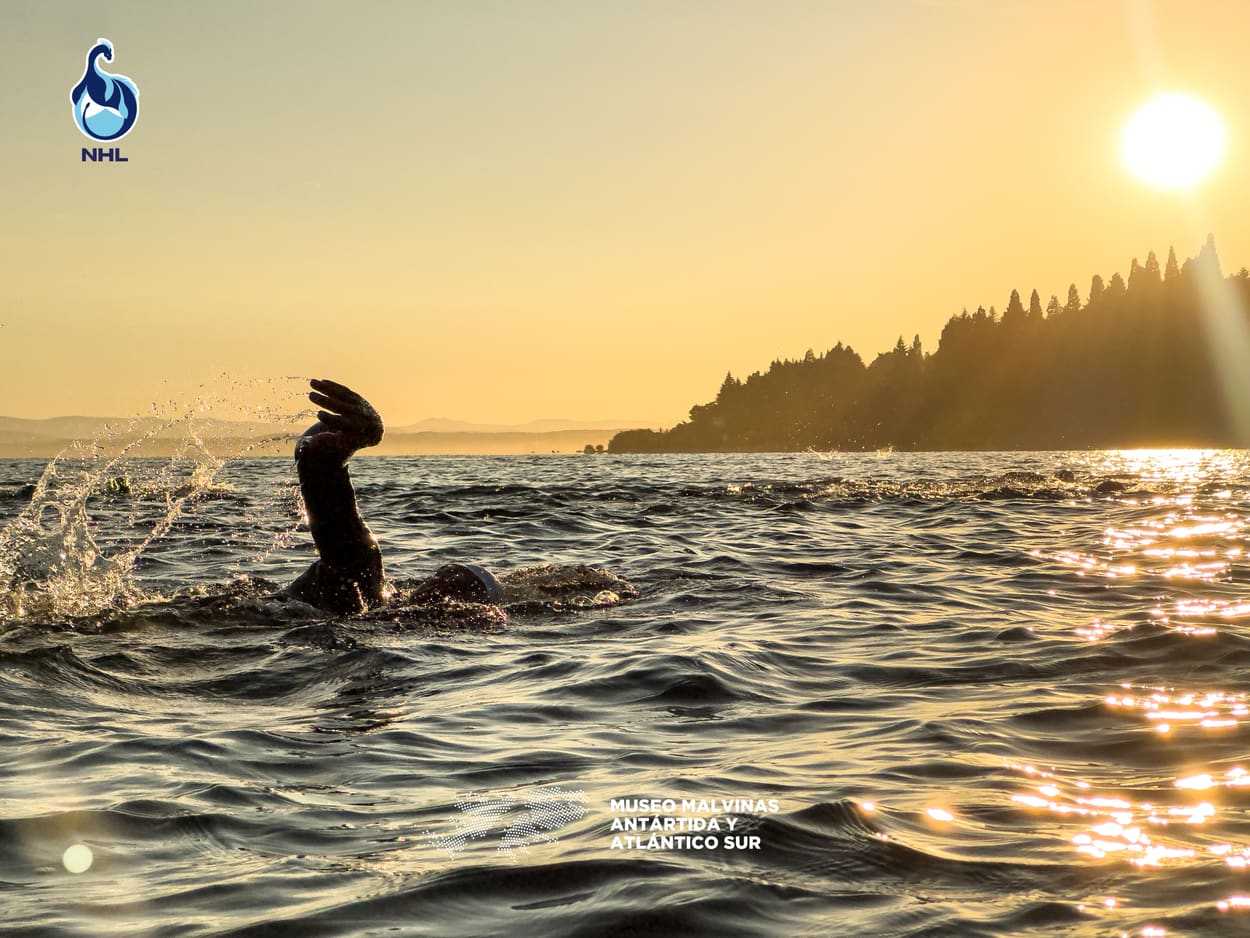 Nadador saliendo del agua a contraluz, en el atardecer sobre el lago Nahuel Huapi