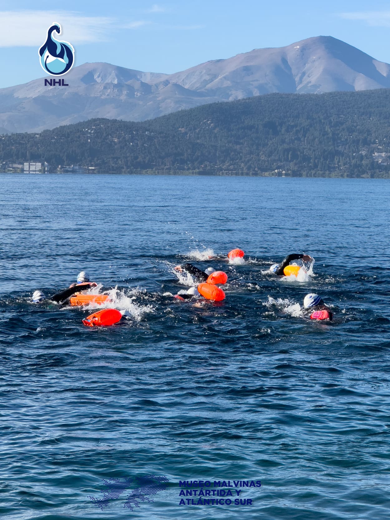 Grupo de nadadores en pleno cruce, con las montañas de Bariloche de fondo
