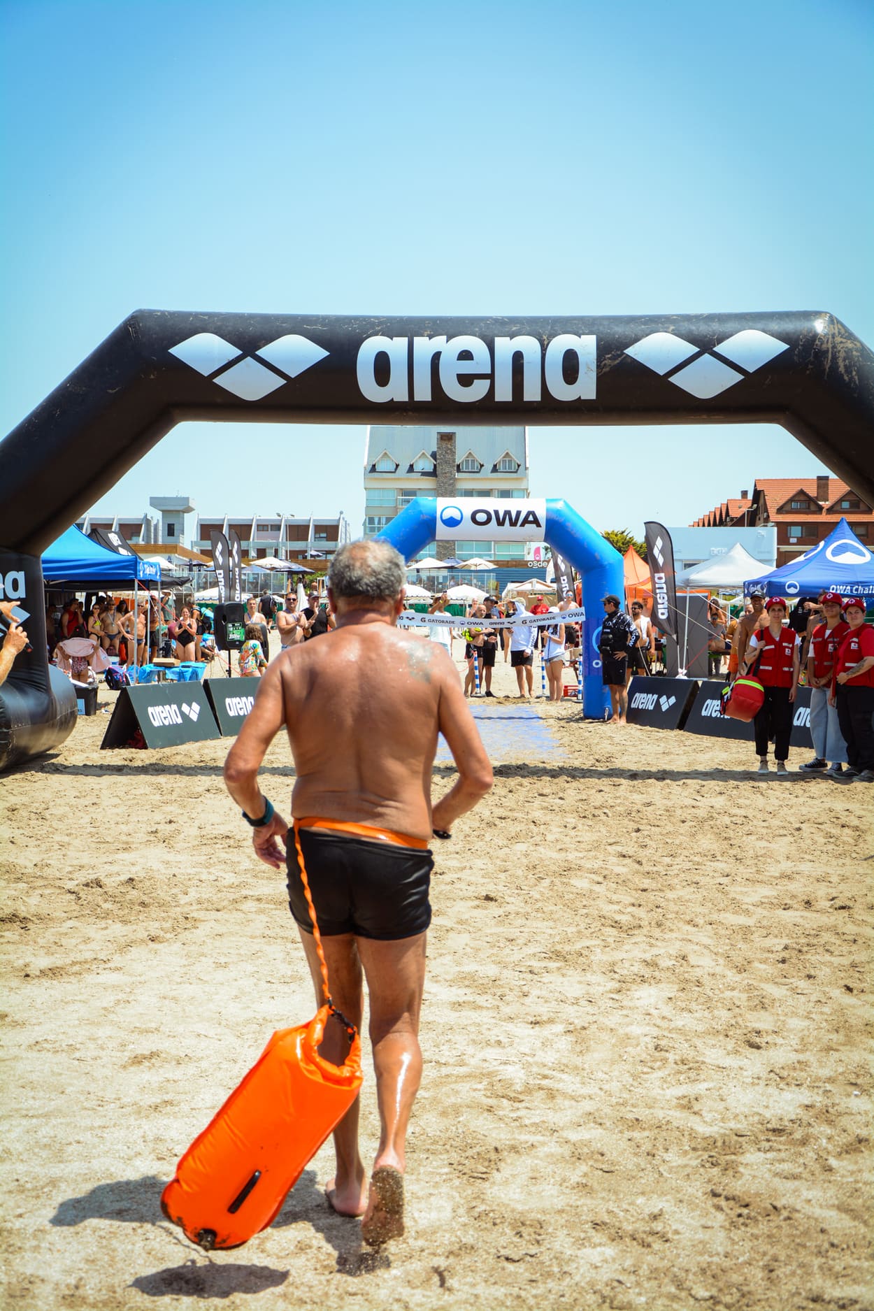 Nadador corriendo hacia la llegada bajo el arco de arena, de espaldas