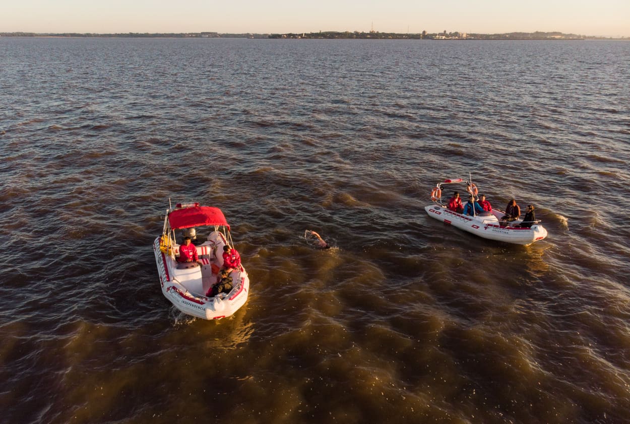 Nadador avanzando en el Río de la Plata con la costa de fondo